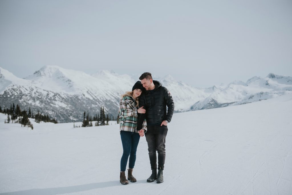 Couple cozy up at the top of Whistler mountain after getting engaged