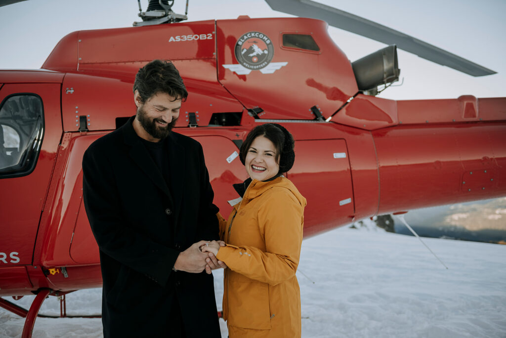A couple admire an engagement ring on Rainbow Glacier after their Whistler Heli Proposa