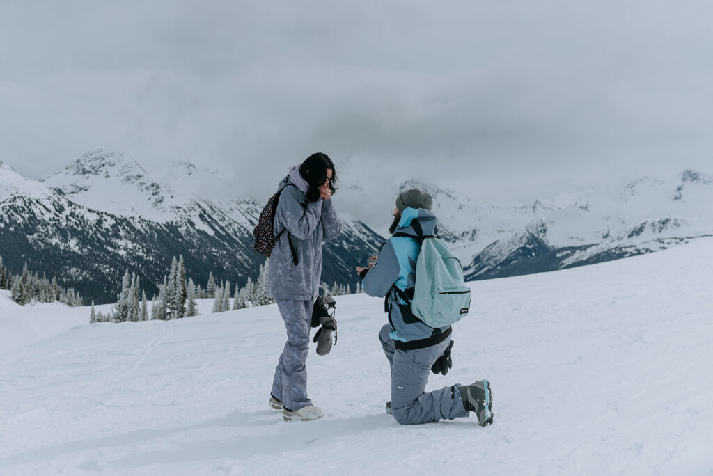 Man proposes to woman on Whistler Mountain in snowboard boots